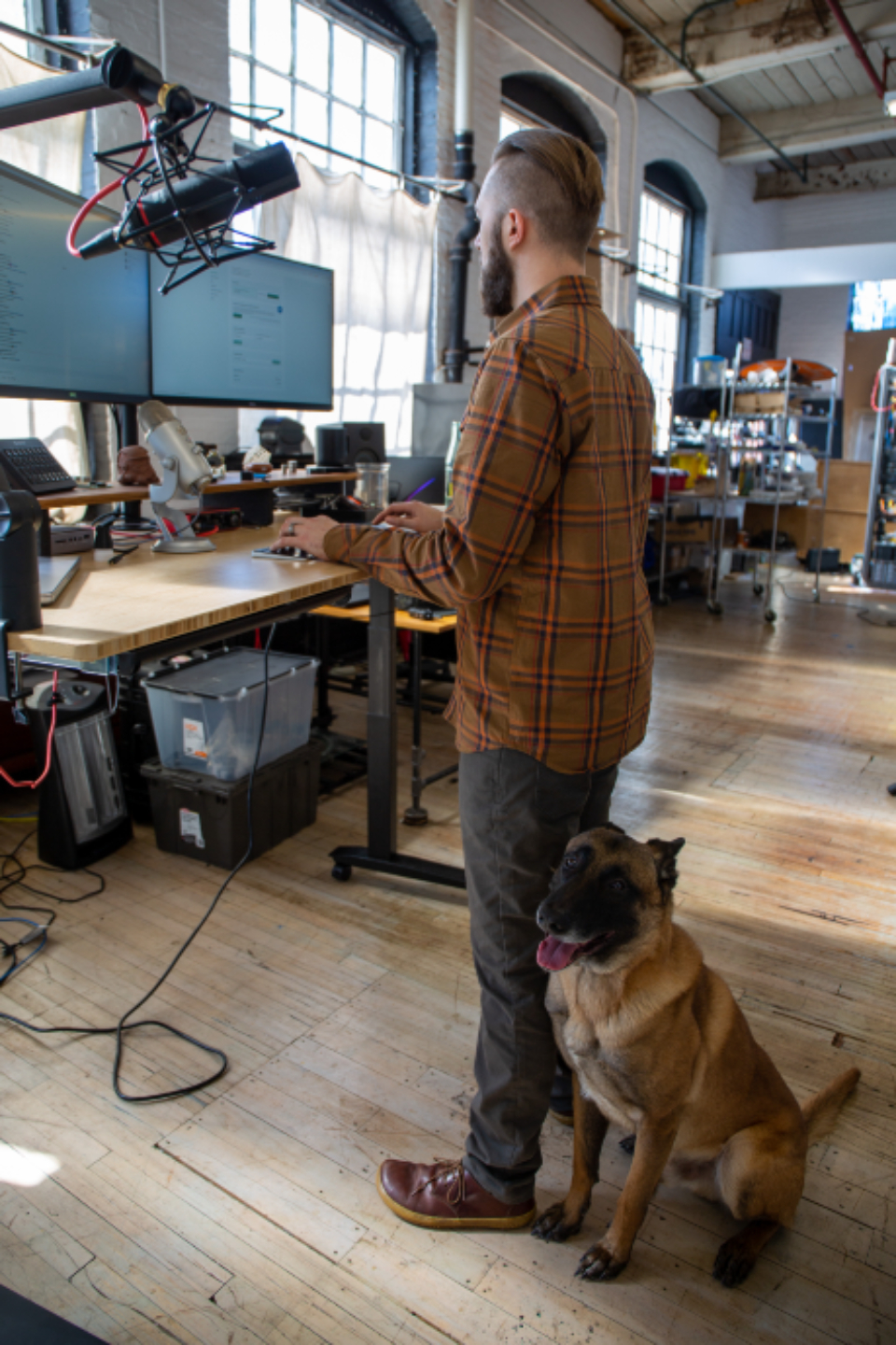 A man working at a desk with his dog beside him